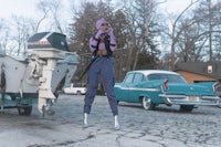 a woman is standing next to a boat and a car