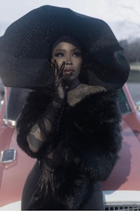 a woman in a black hat standing next to a car