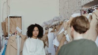 a woman is standing in front of a rack of clothes